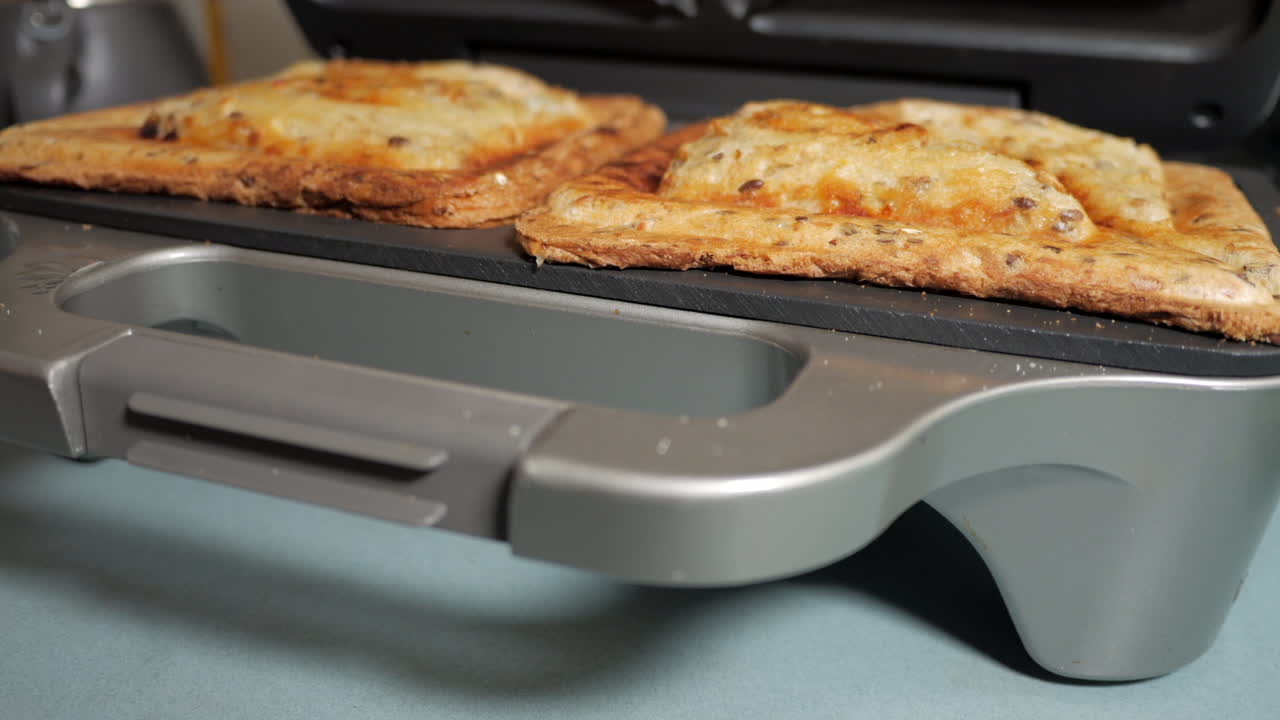 조리된 햄과 치즈 토스트를 보여주기 위해 열리는 샌드위치 메이커