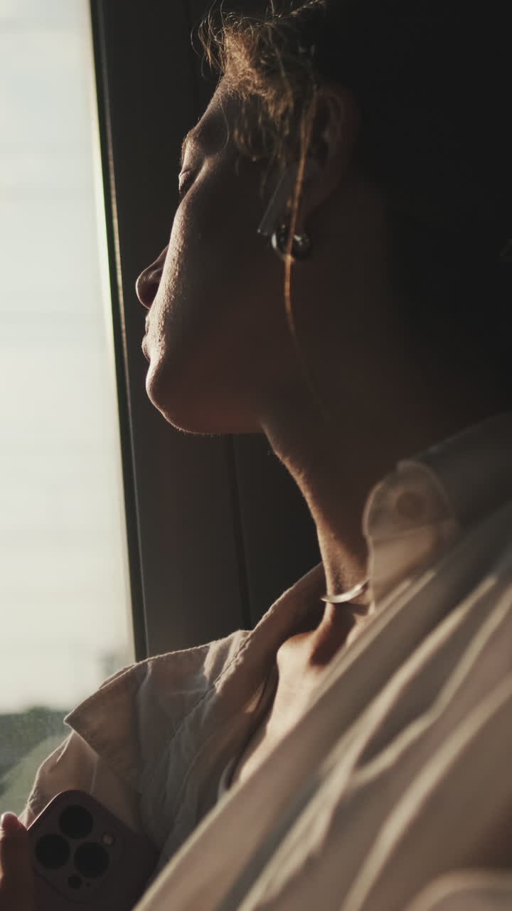 Donna pensierosa che guarda fuori dalla finestra durante un viaggio all'ora d'oro