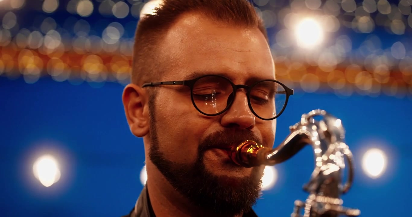Musicista che suona il sassofono sul palco con luci bokeh