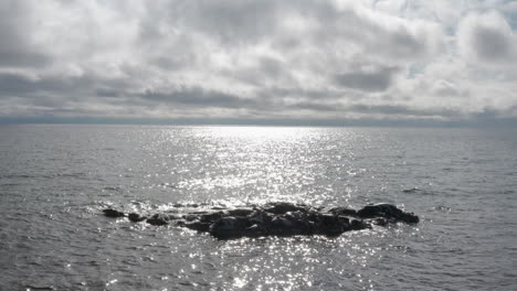 Pequeñas-Rocas-Que-Sobresalen-De-Las-Olas-En-El-Lago-Superior-Rodeadas-De-Olas-En-El-Agua-Hasta-El-Horizonte-En-Un-Día-Nublado