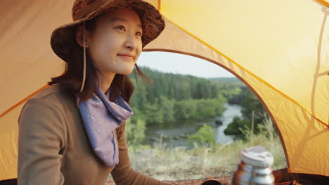asian female tourist drinking tea in tent