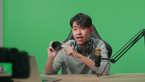 close up of a camera monitor recording asian man with computer reviewing camera len on green screen background