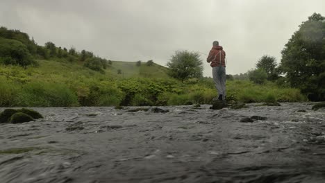 Low-Angle-Aufnahme-Eines-Fliegenfischers,-Der-In-Einen-Schnell-Fließenden-Fluss-In-Der-Schottischen-Landschaft-Wirft