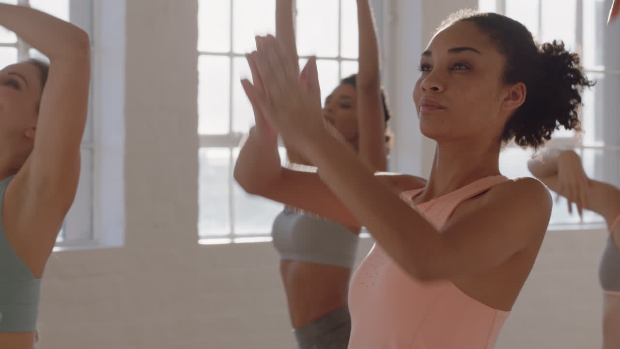 clase de yoga mujer de raza mixta saludable practicando pose guerrera con un grupo de mujeres hermosas disfrutando de un estilo de vida saludable haciendo ejercicio en el gimnasio al amanecer