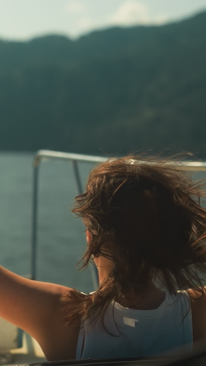 Happy woman looks out of hatch of yacht cabin enjoying relaxation and breathtaking view of nature. Travelling along wide river and tourist recreation