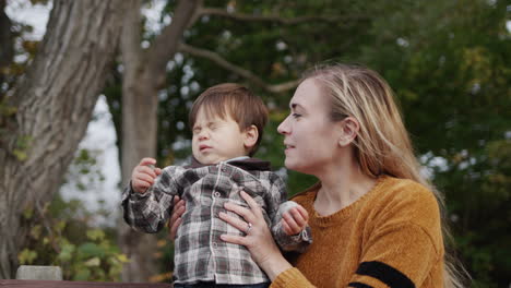 A-young-mother-with-a-little-son-sits-on-a-bench-in-the-park