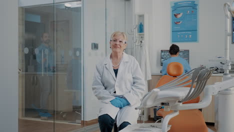 retrato de un dentista con gafas sentado en la oficina de estomatología