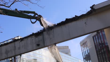 demolition crane spraying water on part it is taking apart