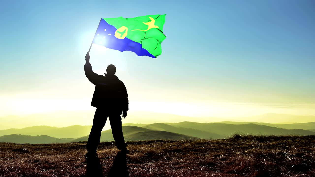 산꼭대기 위에서 크리스마스 섬의 발을 흔들고 있는 성공적인 실루 남자 우승자