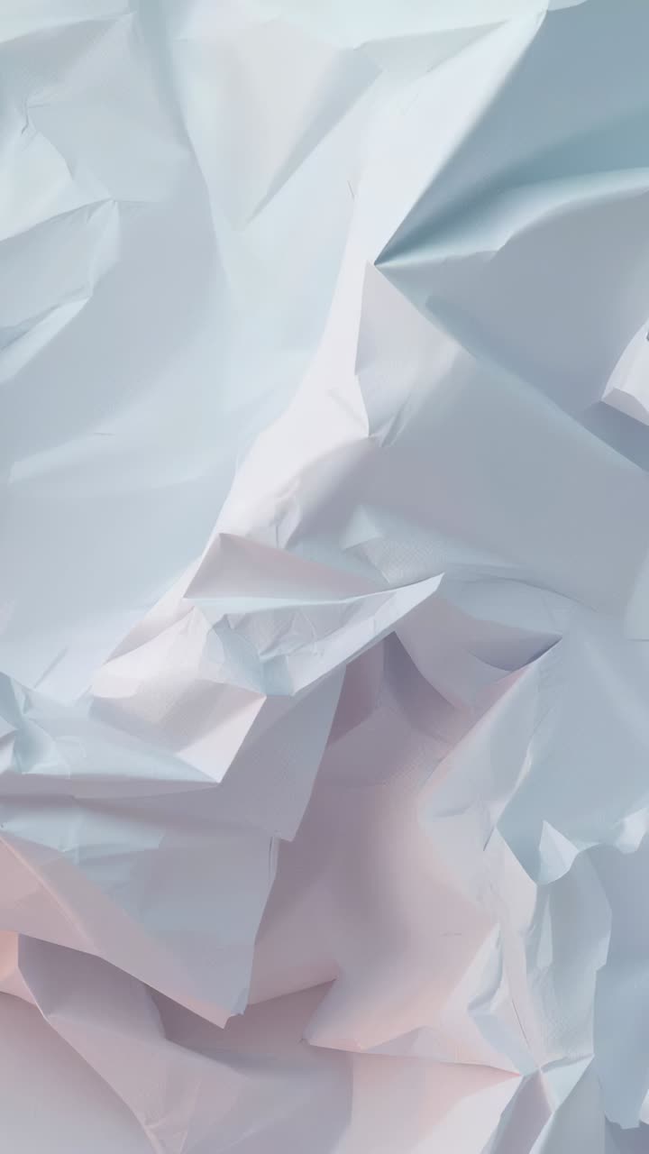 Vertical video: Panning camera upward right, revealing crumpled paper in studio studying texture