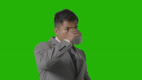 studio shot of businessman in suit holding cup of hot drink against green screen 3