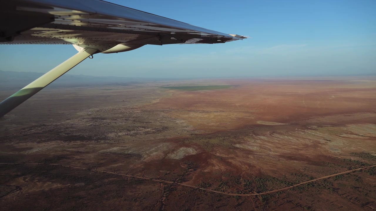 Luftfoto af Amboseli fra et safarifly i Kenya. Afrikansk landskab set fra et fly, der flyver over et tørt, goldt landskab i Afrika under tørkeperioden i et lille fly.