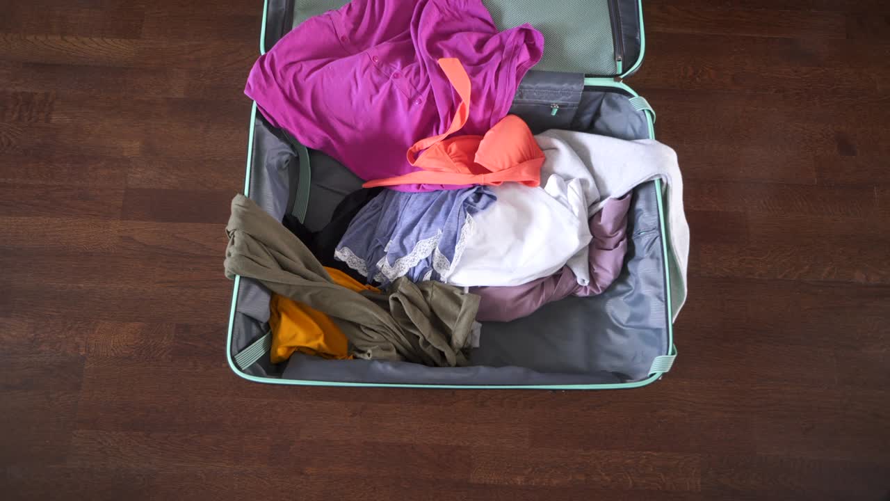Woman quickly throwing clothes into suitcase