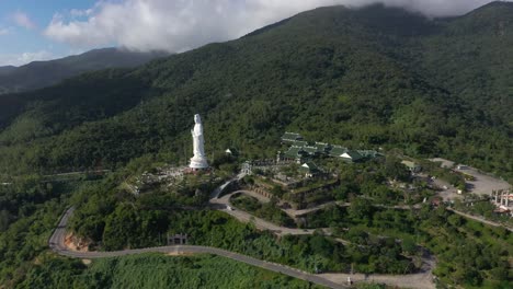 Aerial-rising-high-above-tallest-Lady-Buddha-statue-and-temples-with-huge-mountains-and-ocean-in-Da-Nang,-Vietnam