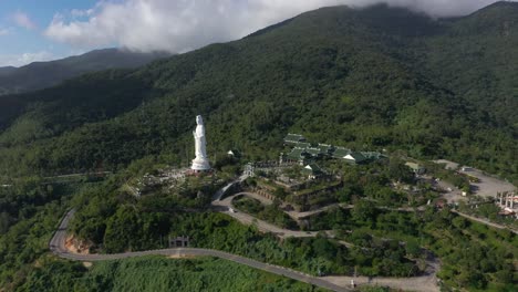 antena que se eleva por encima de la estatua más alta de buda y templos con enormes montañas y océano en da nang, vietnam