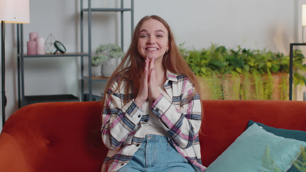 Young adult woman shouting, raising fists in gesture I did it, celebrating success, winning at home