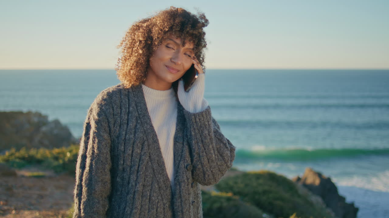 Relaxed woman calling smartphone walking beach closeup. Curly lady strolling