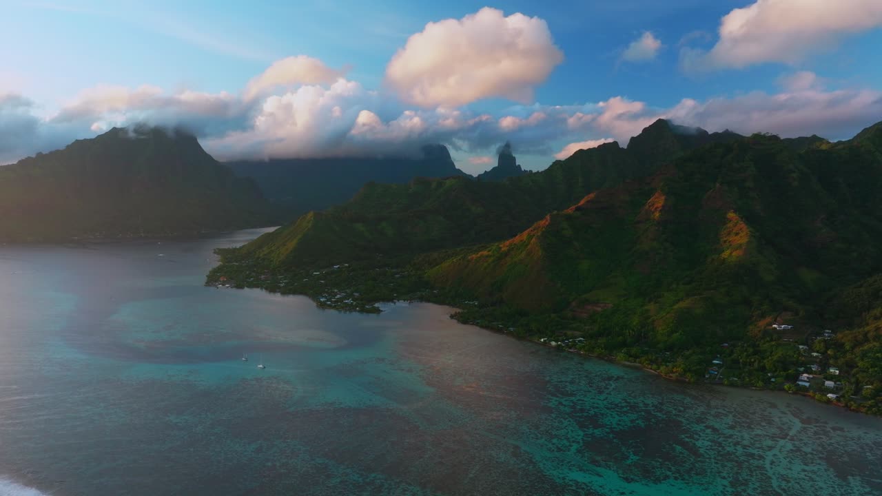 Golden hour sunset Cooks Opunohu Bay Moorea island French Polynesia aerial drone Mount Mauaroa Tohivea Rotui Haapiti jagged mountains clouds boats lagoon coral reef waves Pacific Ocean circle left