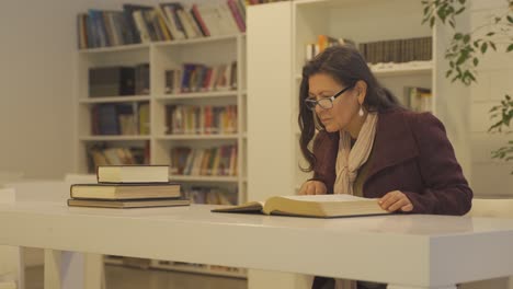 Woman-reading-big-book-in-library.-Handheld