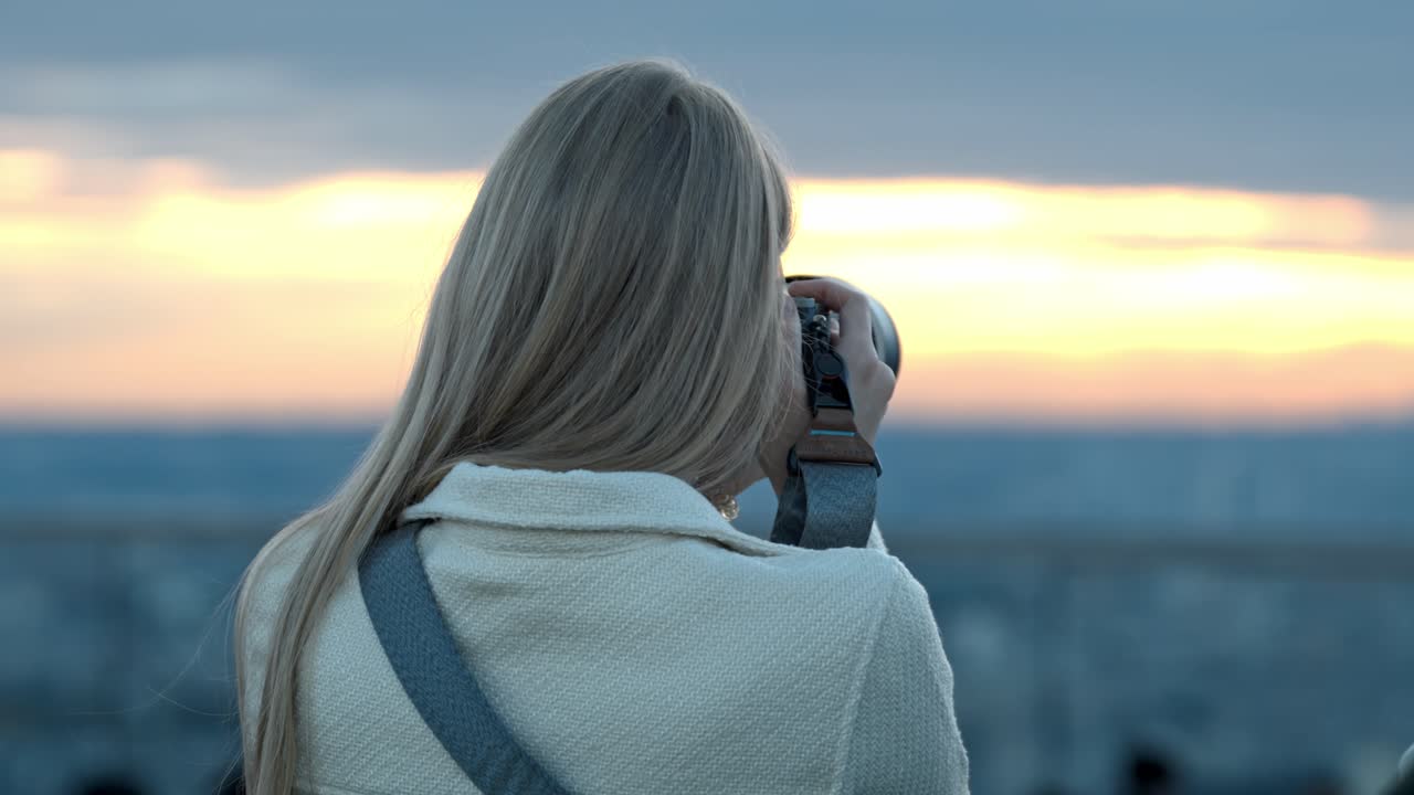 A young woman captures the stunning Tokyo skyline from Shibuya Sky rooftop during sunset.