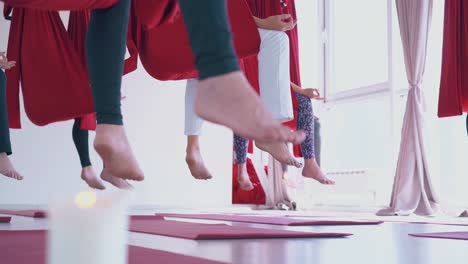 bare women feet sitting in anti-gravity yoga hammocks