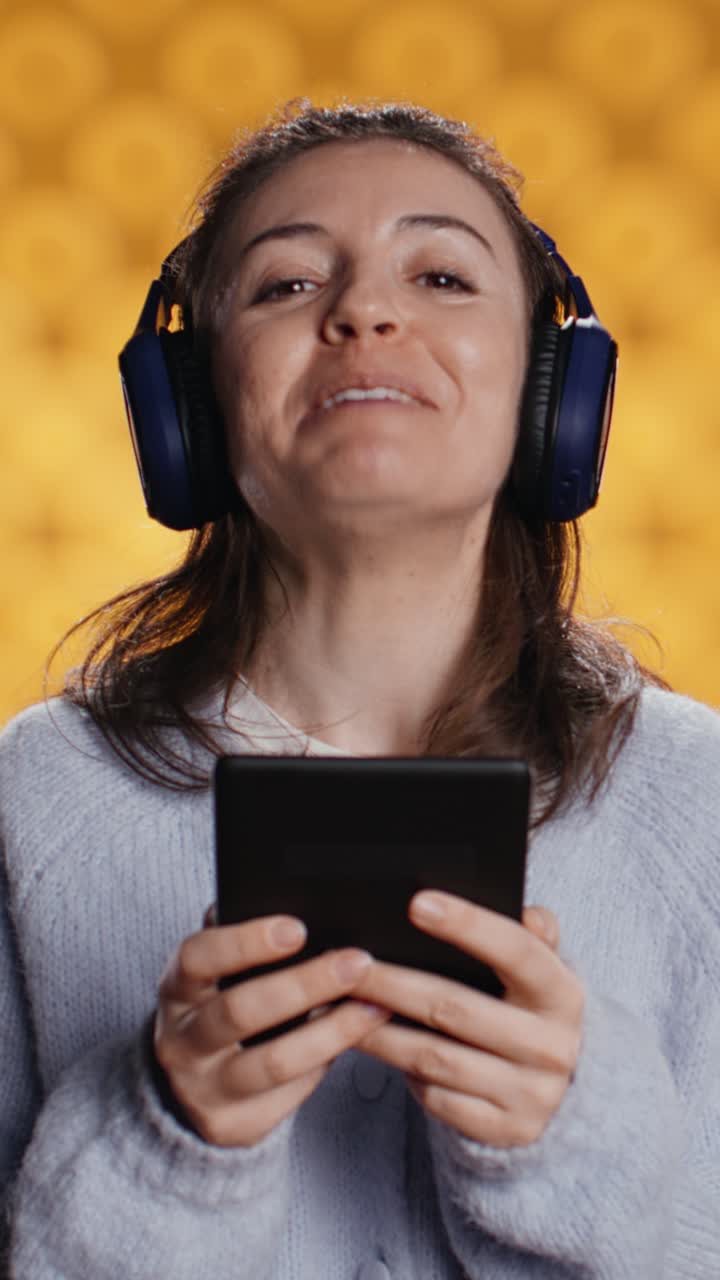 Donna felice che indossa cuffie e usa un tablet