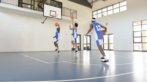 basketball players practicing shots and dribbling on indoor court in gym