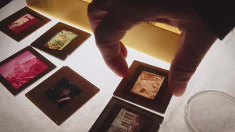 A person&#039;s hand places coloured slides in a plastic binder