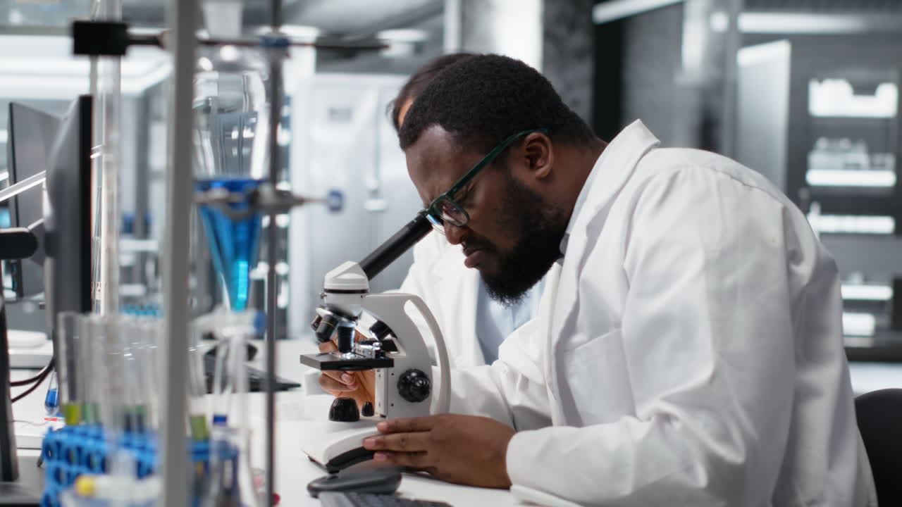 Vertical video Clinical microbiologists using microscope to evaluate cellular structures