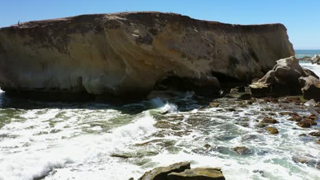 waves cause erosion to form an arch along a rocky shoreline in southern california