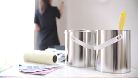 Woman-painting-with-paint-roller,-paint-in-the-foreground