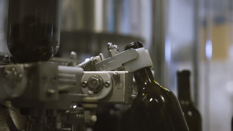 industrial machine arm grabbing empty wine bottles to be washed on assembly line