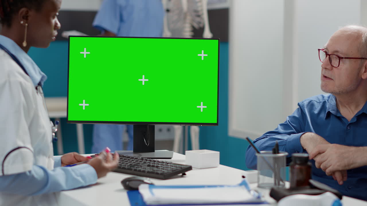 Medico che si consulta con il paziente utilizzando un monitor con green screen