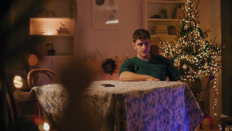 Frustrated-man-with-mobile-phone-sitting-at-table