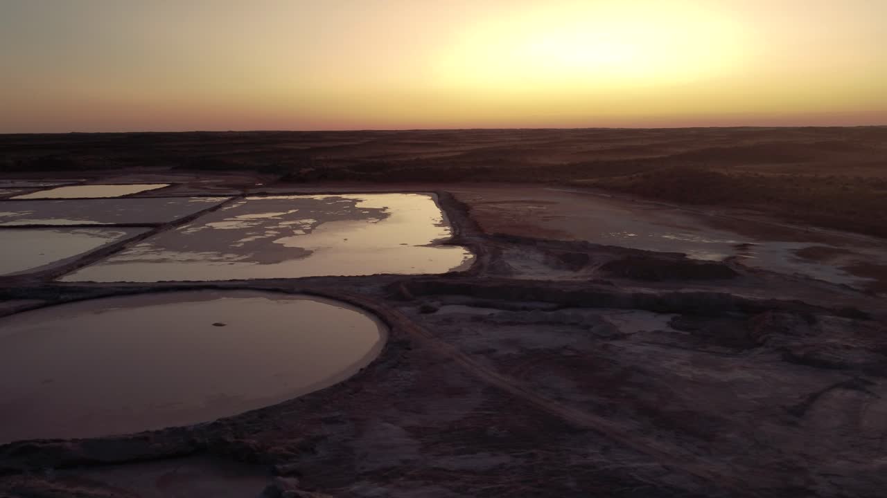 Sideways flyover a salt pan with the reflection of the sunset in the kalahari desert in south africa near to namibia