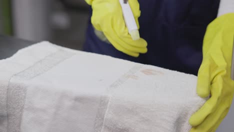 worker in a dry cleaning workshop spraying stain on cotton towel