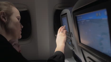 madre enseñando a su hijo a usar el monitor de asiento en el avión