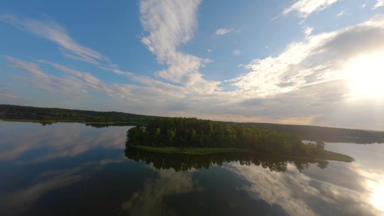 drone se acerca a una isla en el lago baluosas en lituania con aguas tranquilas que reflejan nubes como un espejo