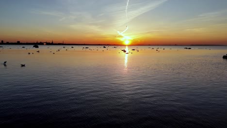 Tallin-Estonia-Drone-Se-Acerca-Al-Horizonte-Del-Paisaje-Urbano-Volando-Sobre-El-Mar-Báltico-Durante-La-Colorida-Puesta-De-Sol