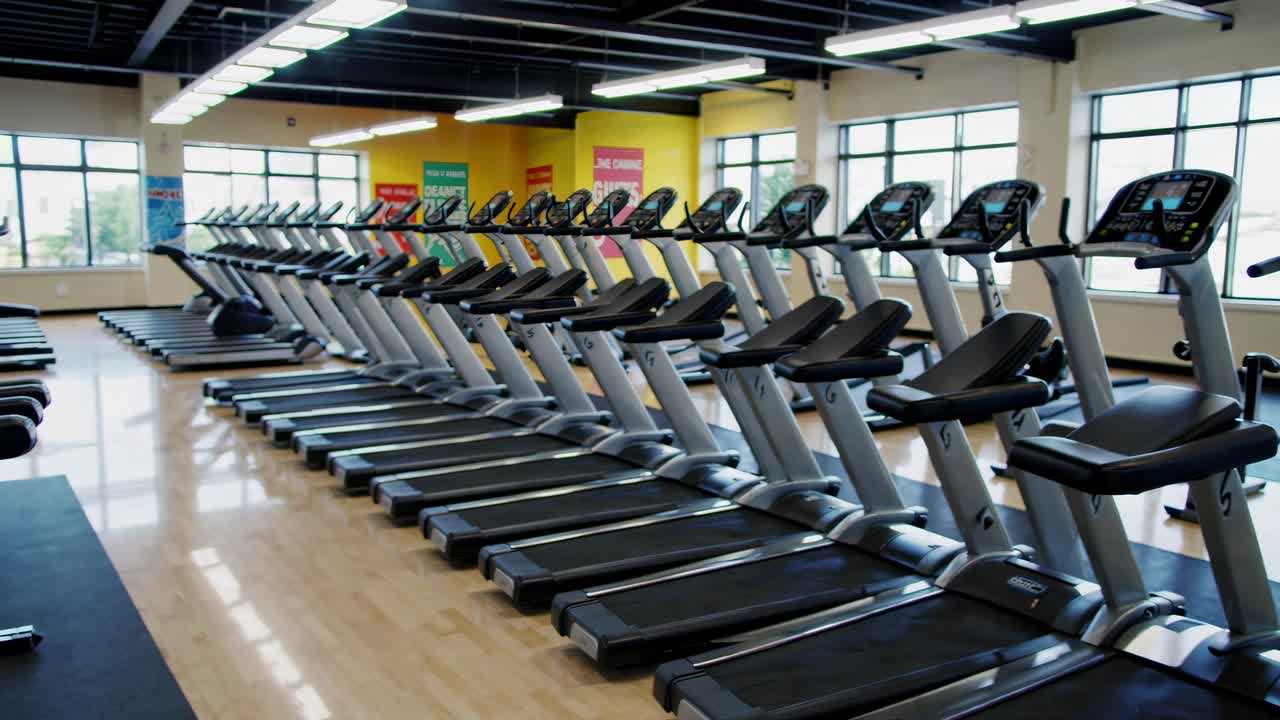 Wide-angle shot of a modern gym with rows of treadmills