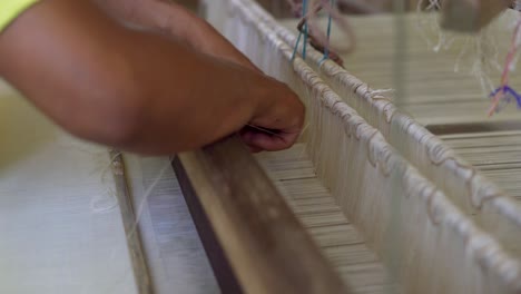 tejer en madera vieja máquina mecánica algodón de seda de cerca en las manos de los trabajadores