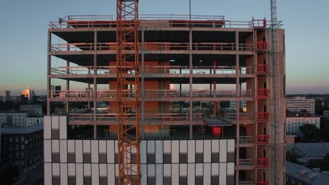 aerial shot of the skyscraper building in the process of construction. in the background working crane and modern city.