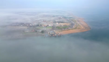 flying over river fog bank towards mist shrouded headland fishing town of fleetwood, lancashire, uk