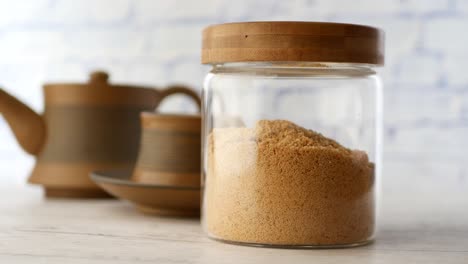 azúcar marrón en frasco de vidrio con tetera y taza