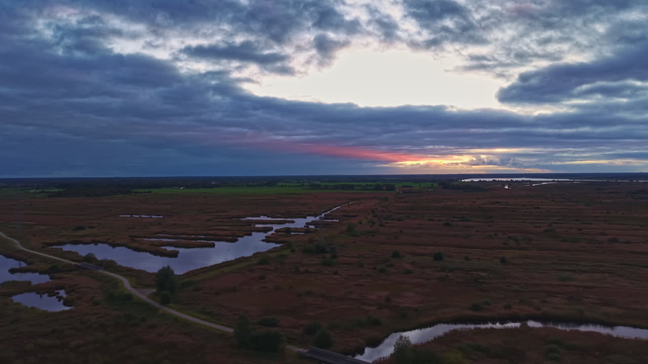 Un tramonto dai colori vivaci tinge una tranquilla palude, mettendo in risalto acque serene e cieli aperti al crepuscolo