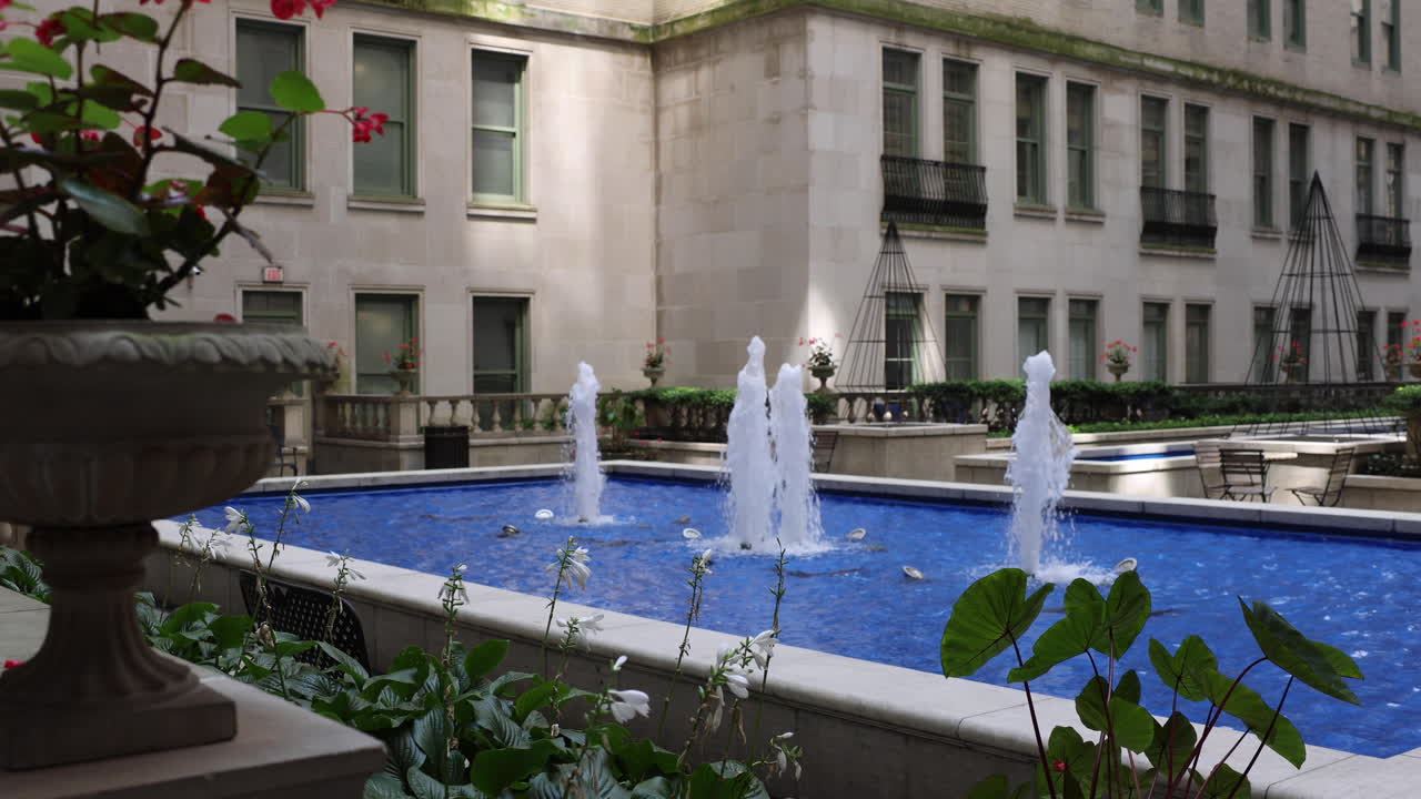 Un patio con una fuente azul y plantas en maceta frente a un edificio.