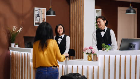 asian hotel staff greeting customer at front desk entrance