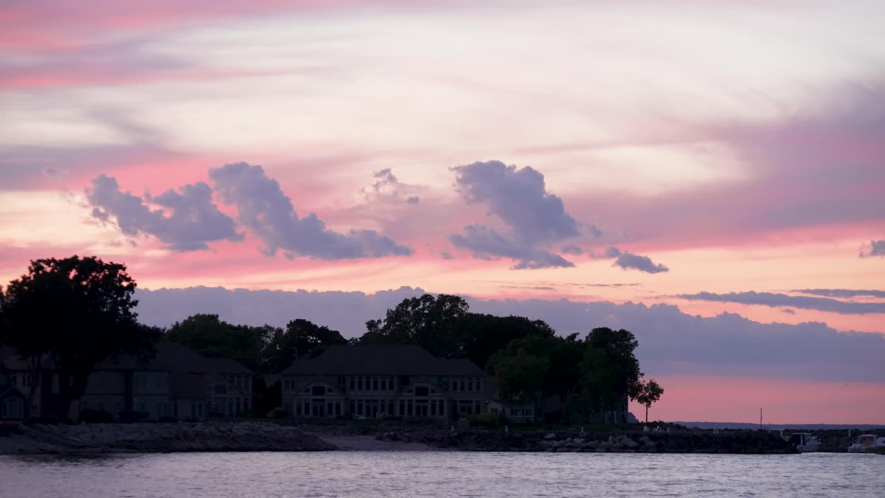 A sunset view of the Glacial Lane condos in Marblehead, Ohio, showing contemporary waterfront homes with Lake Erie in front and sunset skies behind