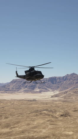 black military helicopter flying over desert landscape