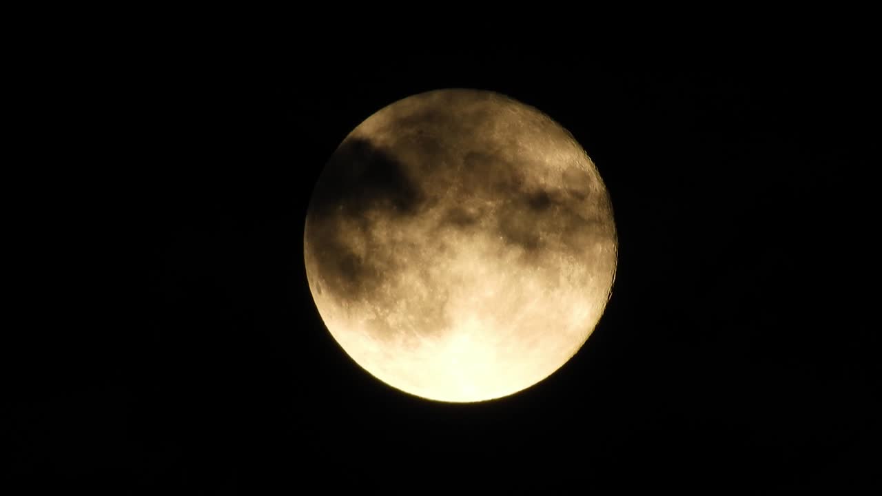 Moon at night with cloud real time. 4k video moon in the black sky.  Clouds passing by moon at night. night sky with cloudy weather